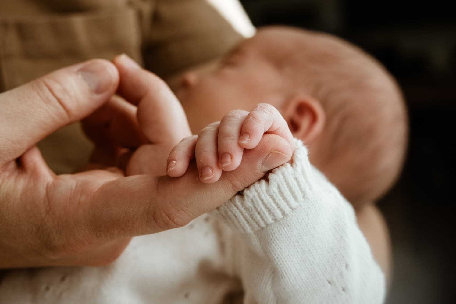 A baby holding their parent's hand